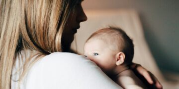 woman in white shirt carrying baby