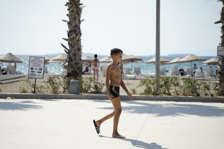 topless man in black shorts walking on sidewalk during daytime