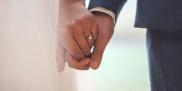 man in black suit jacket holding hands with woman in white dress