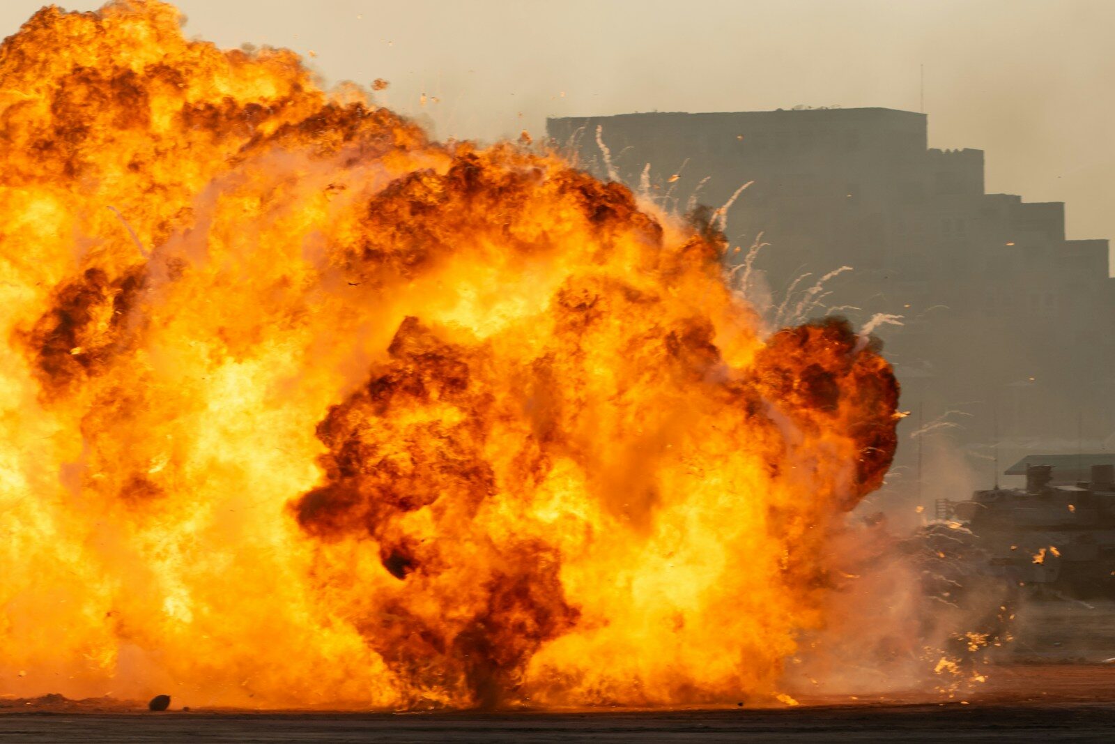A massive orange fireball erupting in front of a silhouetted building