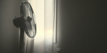 white wall fan turned on near white window blinds